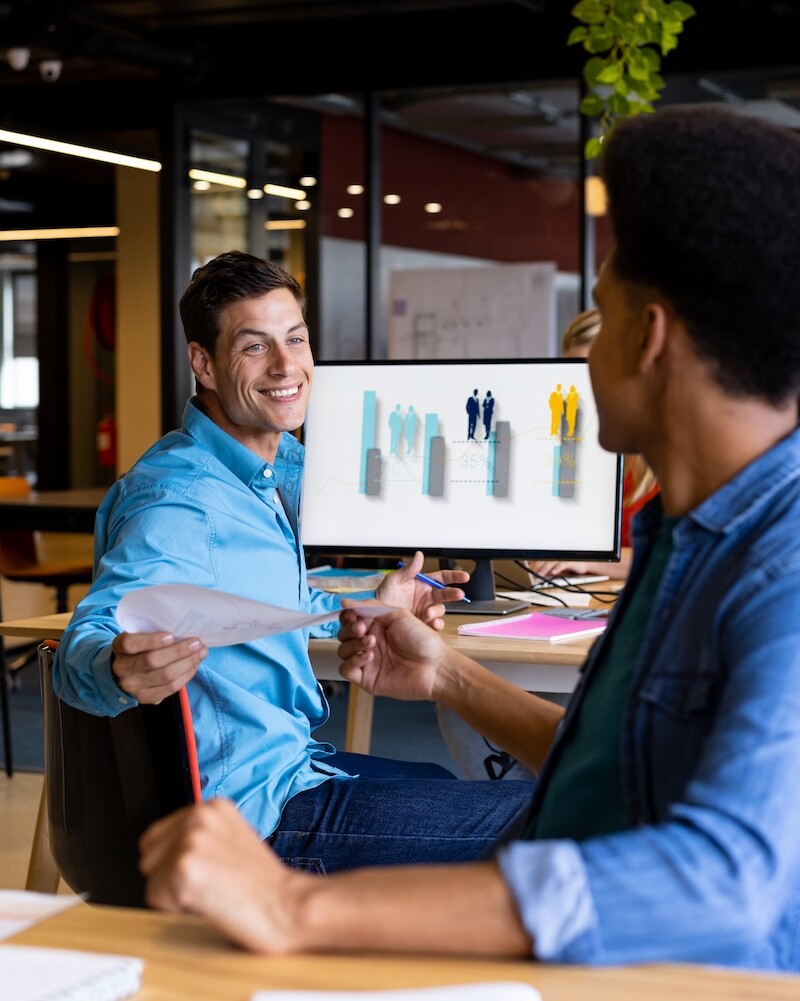 WhatzIndustry - happy diverse male colleagues at desks passing doc 2025 04 03 13 28 41 utc uai
